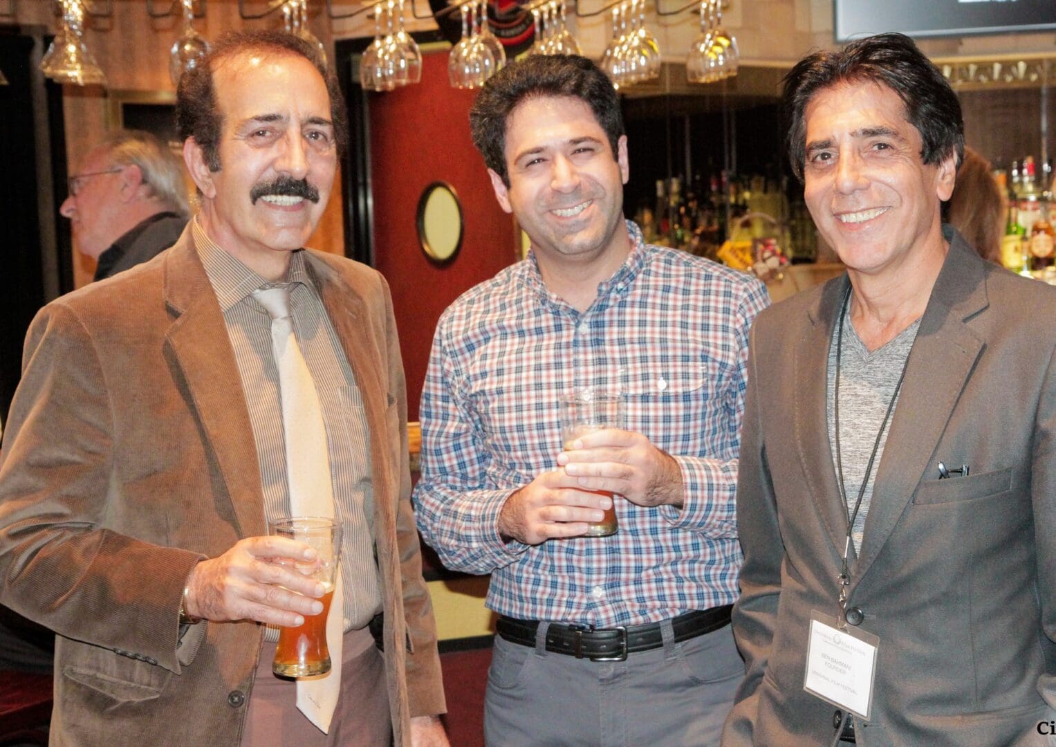 Three men are posing for a picture while holding drinks.