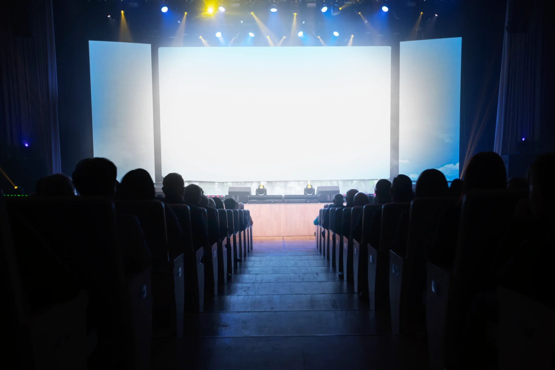 A large screen with people sitting in front of it