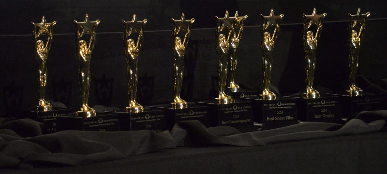 A row of gold statues sitting in front of a black wall.