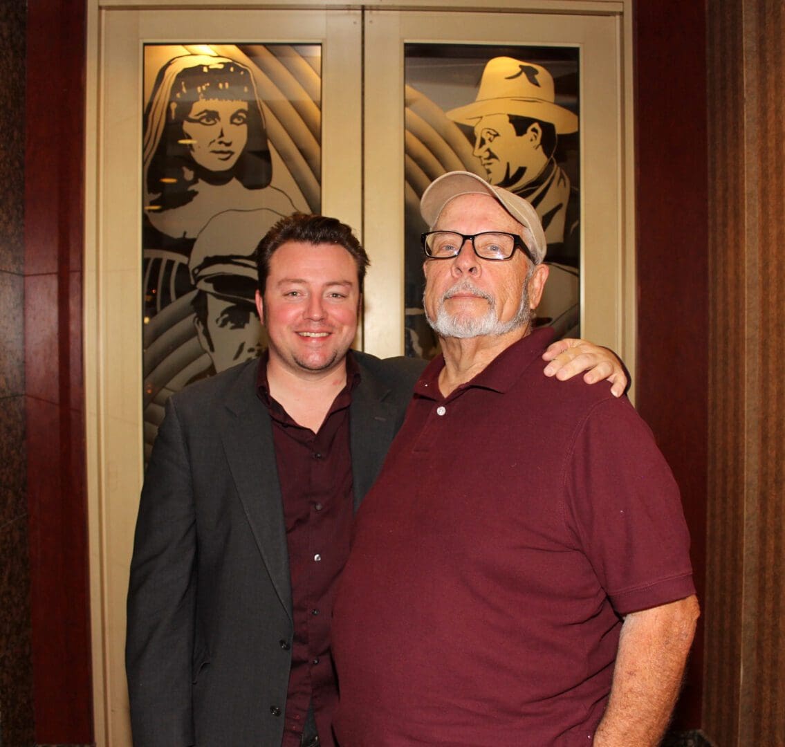 Two men standing next to each other in front of a painting.