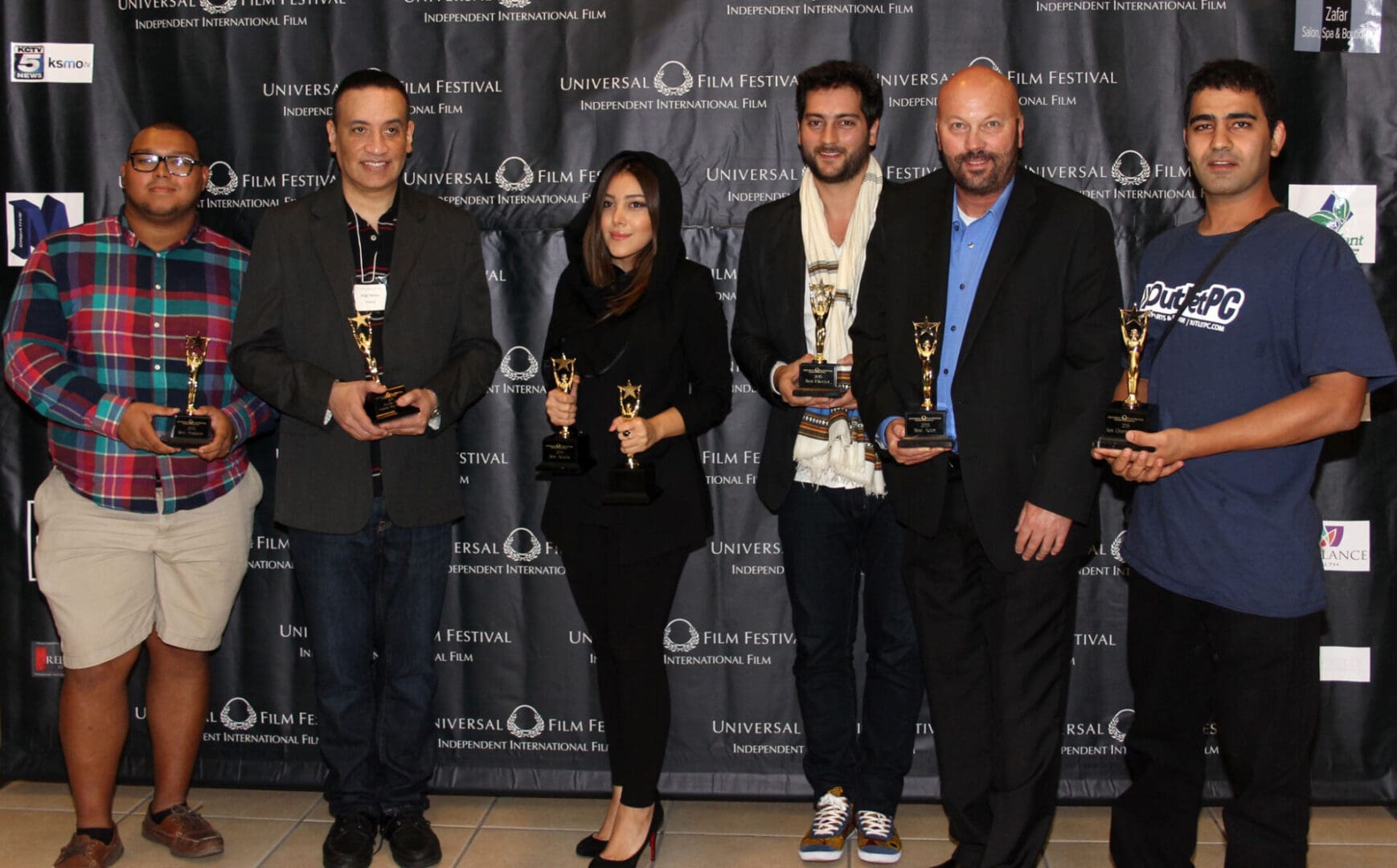 A group of people holding awards in front of a black backdrop.