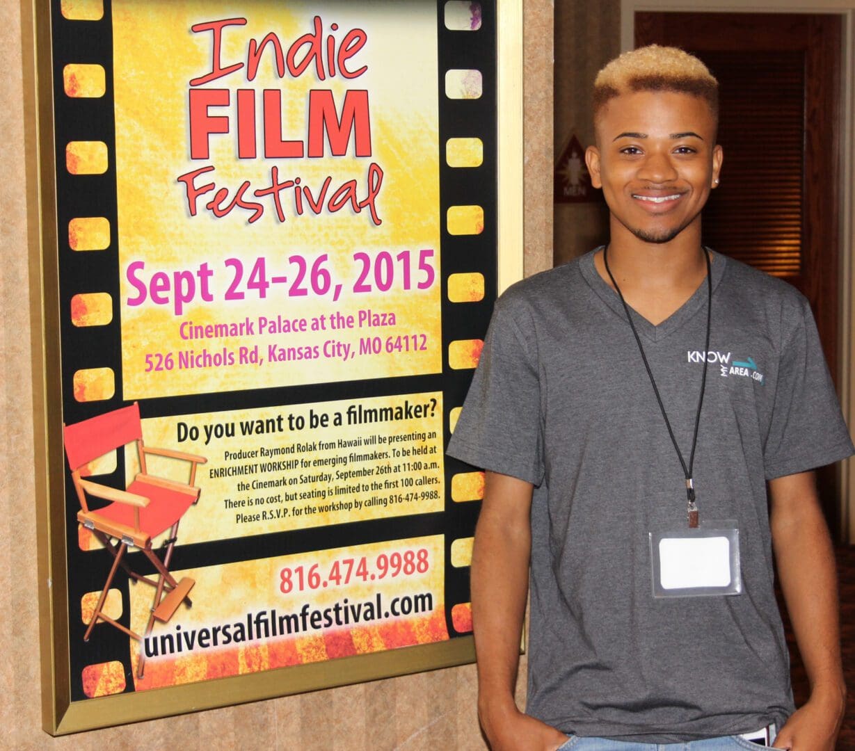 A man standing in front of an advertisement for the indie film festival.