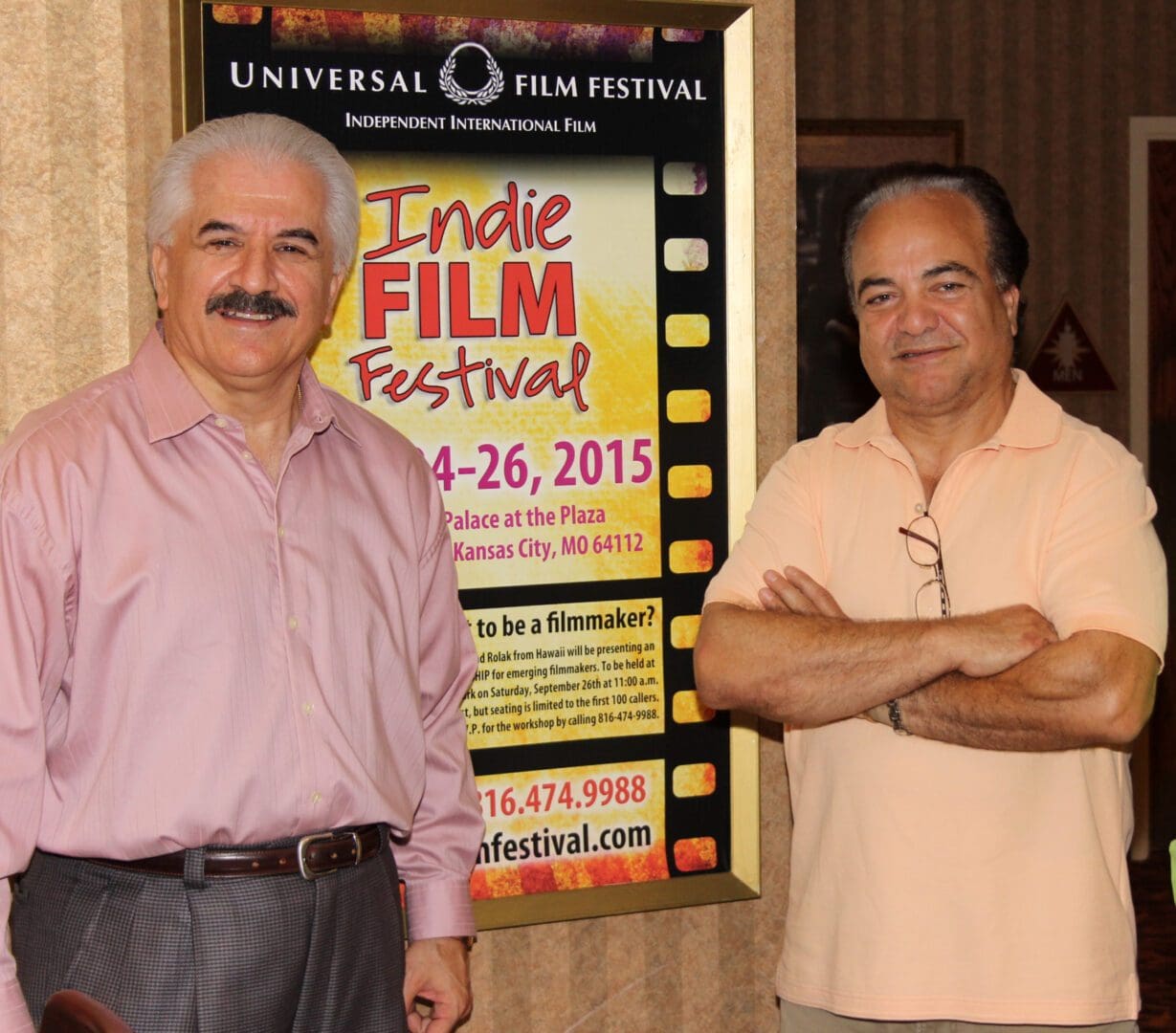 Two men standing in front of a poster for the indian film festival.