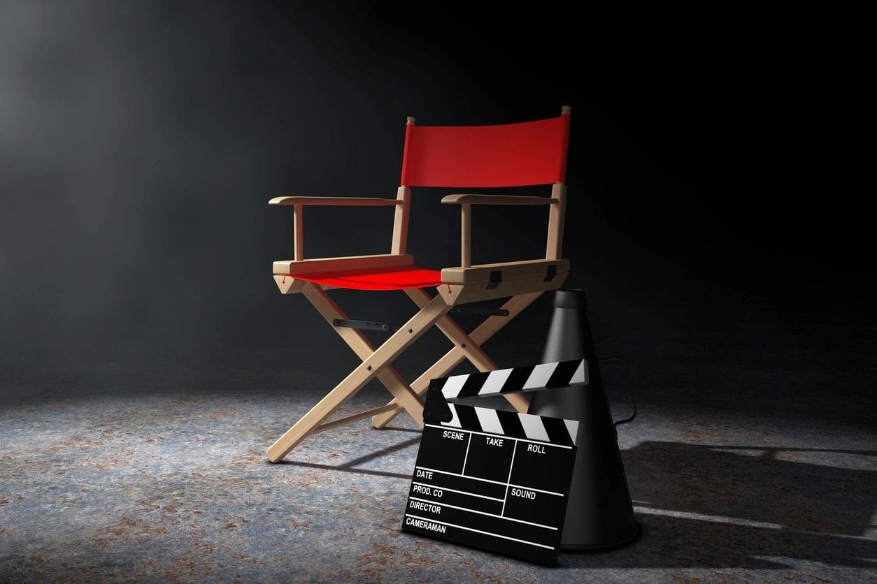 A director 's chair and movie clapper board in an empty room.