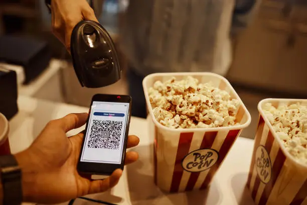 A person using their phone to pay for popcorn.