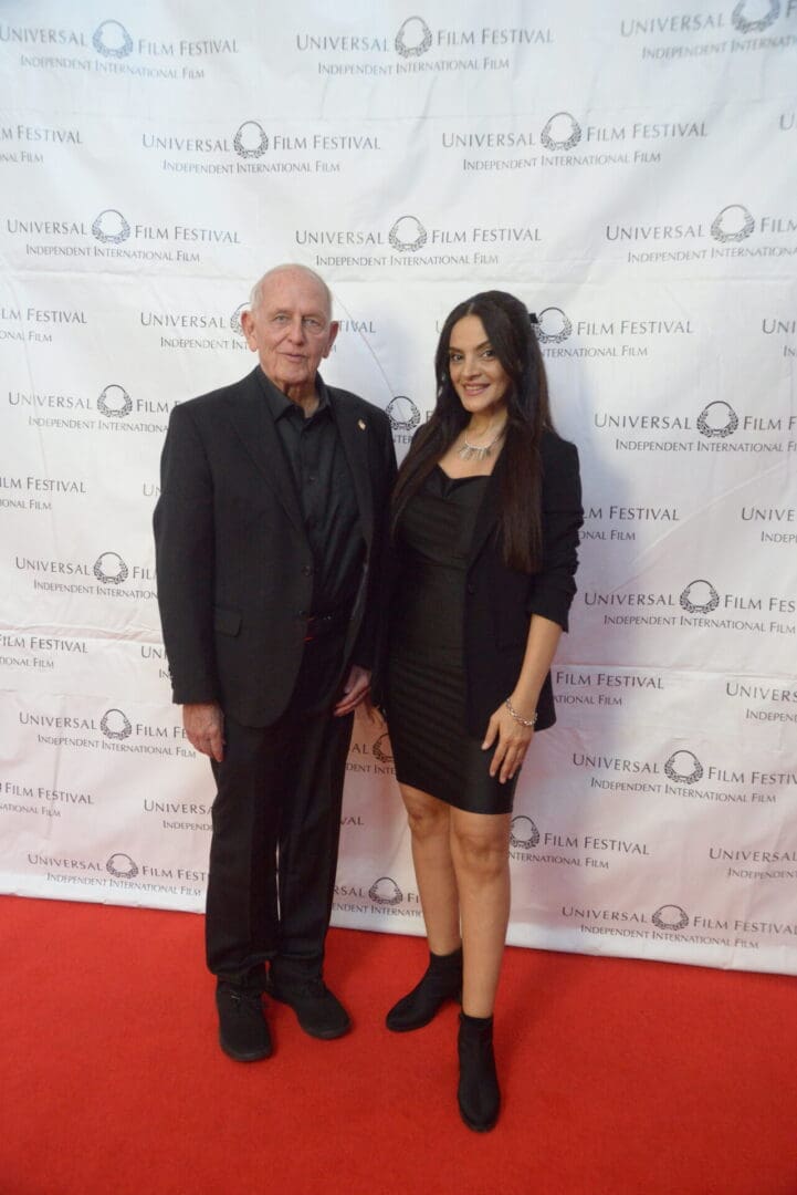 A man and woman posing for the camera on a red carpet.