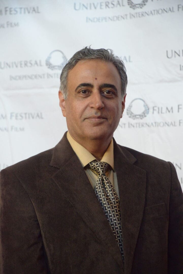 A man in a suit and tie standing on the red carpet.