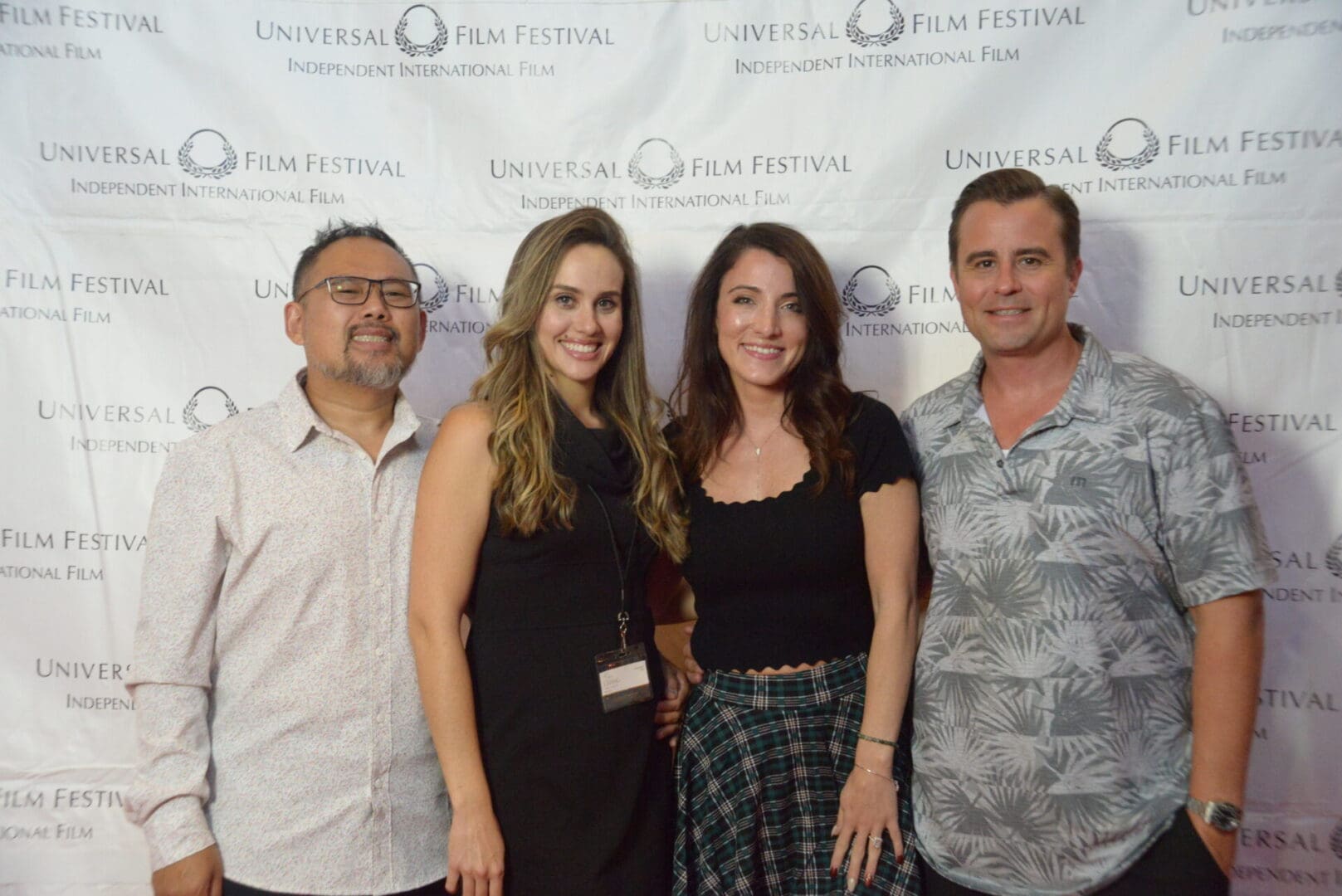 A group of people standing in front of a white wall.