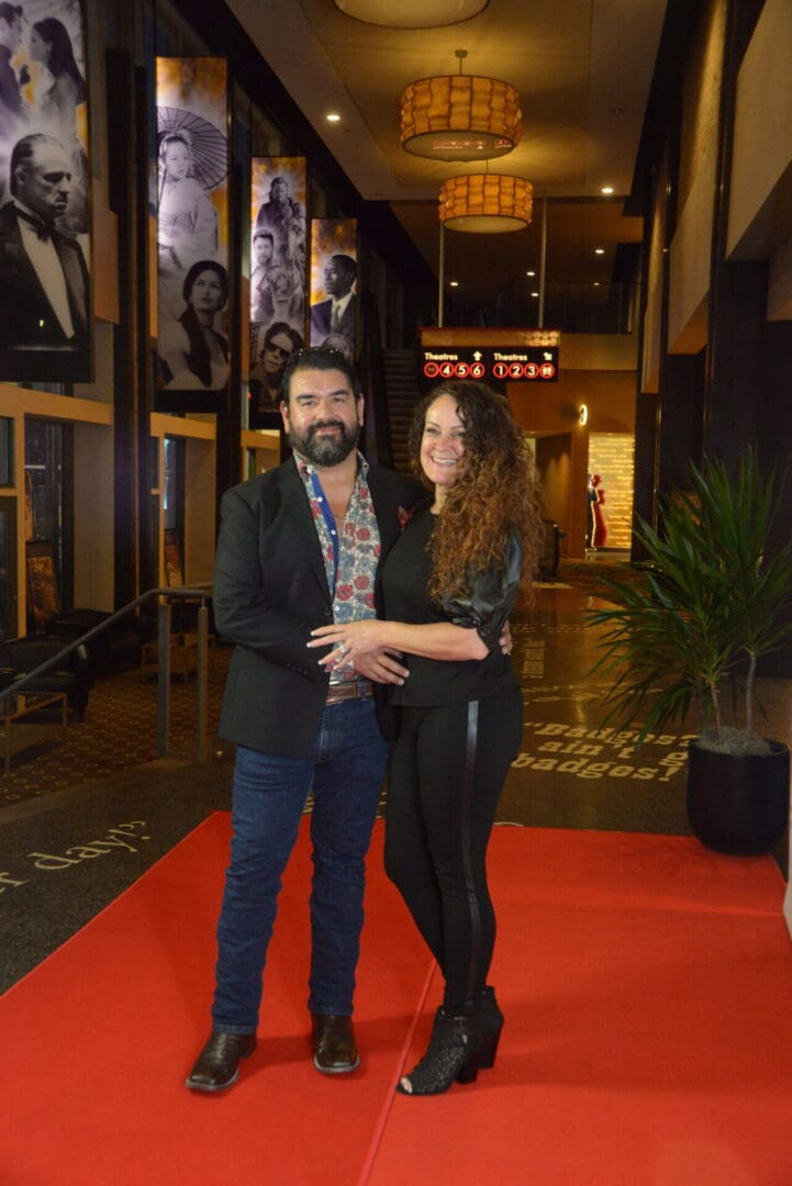 A man and woman posing for the camera on a red carpet.