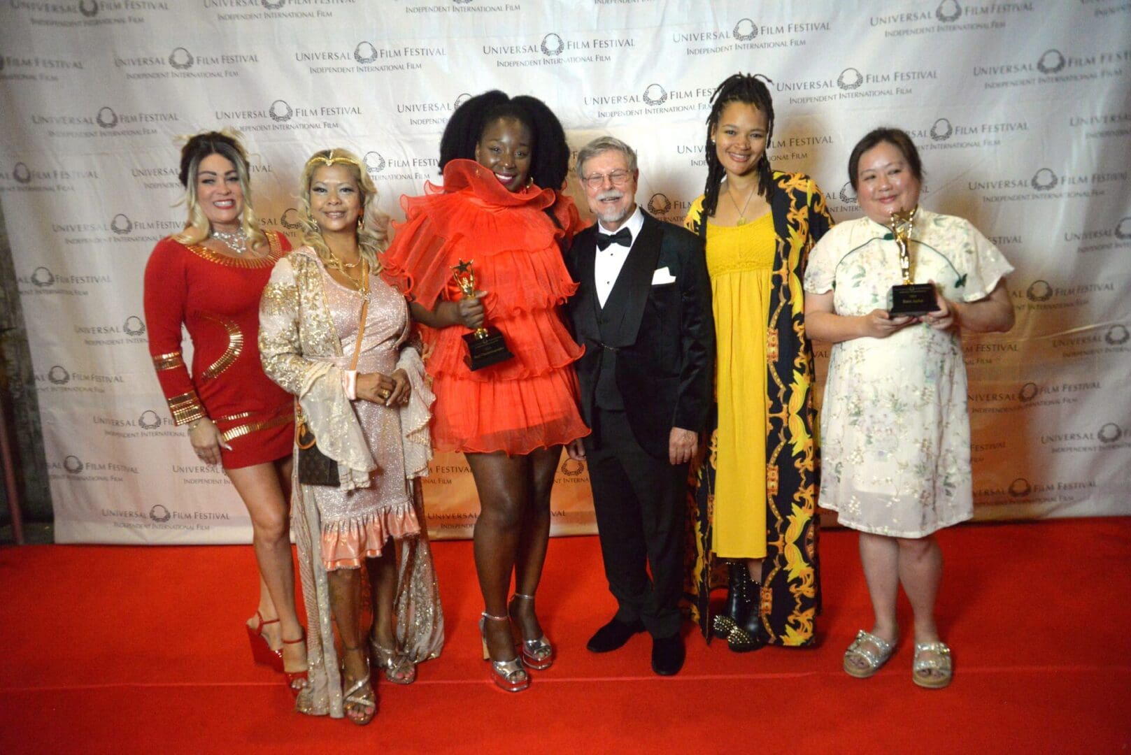 A group of people standing on the red carpet.